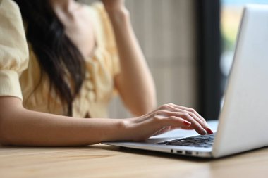Bilgi aramak için dizüstü bilgisayarda yazı yazan tanınmayan genç kadın ellerini kapat.