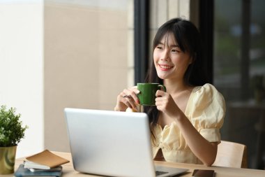 Çekici, genç Asyalı kadın elinde kahve fincanıyla ve yüzünü rüya gibi bir ifadeyle çeviriyor..