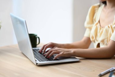 Bilgi aramak için dizüstü bilgisayarda yazı yazan tanınmayan genç kadın ellerini kapat.