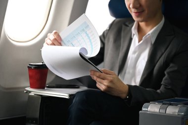 Genç işadamı görevlerine odaklandı, uçuş sırasında uçakta otururken belgeleri gözden geçirdi..