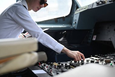 Erkek pilotun kalkışa hazırlandığı, kokpitteki düğmeleri ayarladığı kesikli bir çekim..