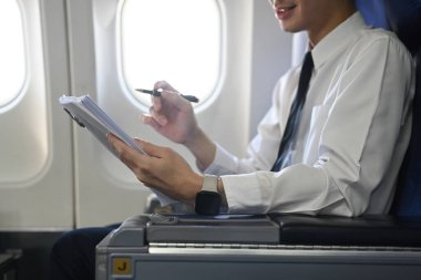 Genç işadamı uçuş sırasında önemli belgeler okuyor. İş seyahati kavramı.