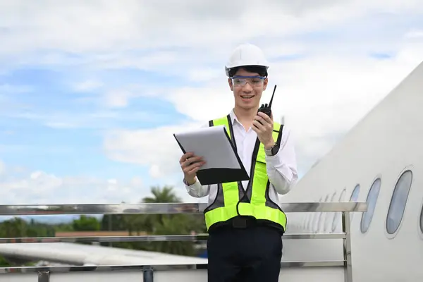 stock image Smiling male air traffic controller with walkie talkie standing in front of airplane on runway.