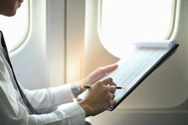 Pilot uçuş planlarını veya diğer önemli bilgileri gözden geçirirken bir uçak kabininde otururken görüntüyü kapat.