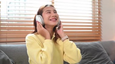 Telsiz kulaklıklı güzel Asyalı kadın en sevdiği müziği dinliyor ve şarkı söylüyor..