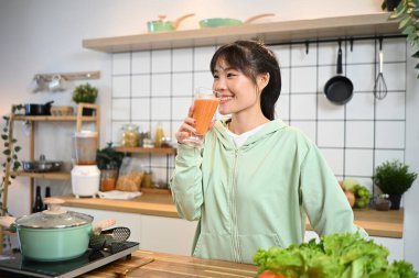 Güzel genç atletik kadın mutfakta sağlıklı meyve suyu içiyor..