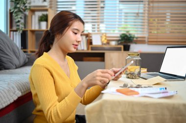 Rahat bir oturma odasında oturan genç bir kadın birikmiş tasarrufların keyfini çıkarıyor. Gelecek için planlama.