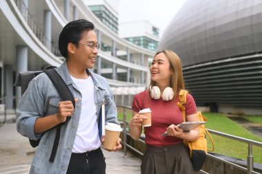 Modern kampüste birlikte yürüyen iki mutlu öğrenci, keyifli bir sohbetin tadını çıkarıyorlar..