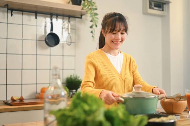 Modern bir mutfakta yemek hazırlayan mutlu genç Asyalı kadın..