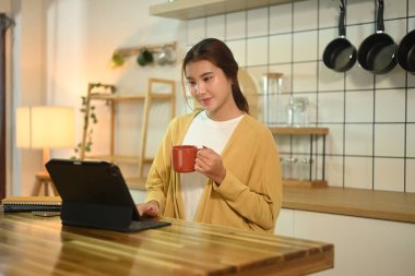 Kahve içen ve sabahları mutfak masasında dizüstü bilgisayarla çalışan güzel bir kadın..