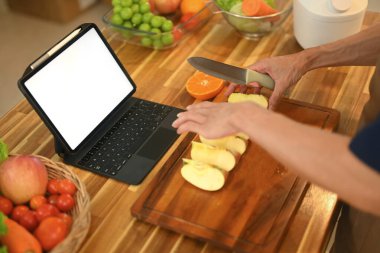 Mutfakta sağlıklı yemek yaparken dijital tablette online tarifi takip eden bir adam..