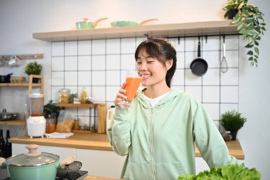 Güzel, genç bir kadın mutfakta çalıştıktan sonra sağlıklı meyve suyu içiyor..