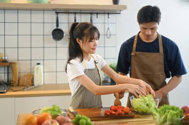 Neşeli genç çift en az mutfakta sağlıklı sebze salatası hazırlıyor..
