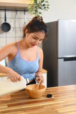 Sağlıklı beslenme için mısır gevreğiyle bir kaseye süt döken kadın. Kahvaltı, yemek ve yaşam tarzı konsepti.