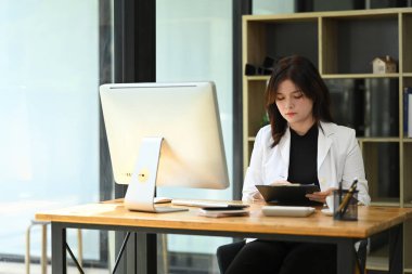 Ofisteki istatistik belgelerini inceleyen konsantre genç iş kadını..