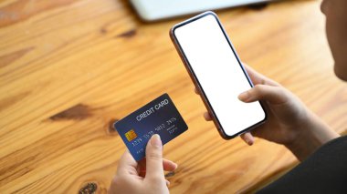 Elinde akıllı telefon, kredi kartı, e-ticaret ve dijital ödeme konsepti olan kadınlara yakın çekim.