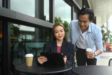 Genç iş arkadaşları açık kafede proje sonuçlarını tartışıyor.