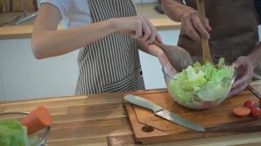 Kırpılmış genç çift, mutfakta birlikte lezzetli ve sağlıklı bir salata hazırlamaktan zevk alır..