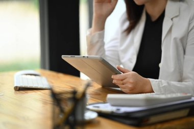 Modern iş yerinde dijital tablet kullanan beyaz takım elbiseli profesyonel iş kadını.