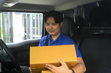 Kargo işçisi detayları kontrol ediyor ya da karavanda paket düzenliyor. Ulaştırma ve dağıtım hizmetleri kavramı.