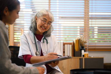 Olumlu kıdemli doktor kadın hastaya tıbbi sonuçları bildiriyor. Tıbbi ve sağlık hizmetleri kavramı.