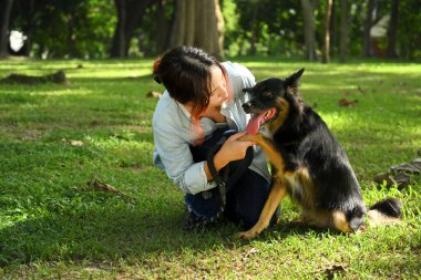 Köpeğin patisini nazikçe tutan genç bir kadının fotoğrafı. Sahibi ile evcil hayvanı arasında sevgi dolu bir bağ..