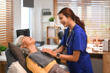 Ciğerlerindeki salgıları gevşetmek ve boşaltmak için kıdemli hastaya göğüs vuruşu yapan bir fizyoterapist..