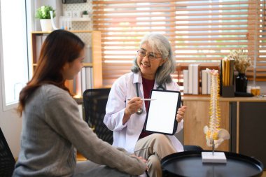 Olgun kadın doktor hastasına dijital tablet üzerinde tıbbi test sonuçları gösteriyor. Sağlık hizmetleri kavramı.