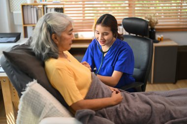 Gülümseyen kadın pratisyen hekim klinikte stetoskop kıdemli hastasıyla muayene ediyor..