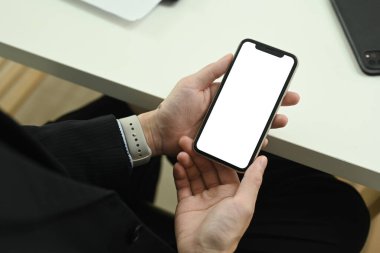 Yakın plan, ofis masasında oturan akıllı telefonlu genç bir işadamının fotoğrafı..