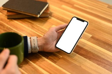 Yakın plan, ofis masasında oturan akıllı telefonlu genç bir işadamının fotoğrafı..