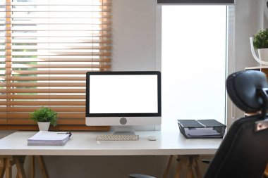 Boş bilgisayar monitörü ve ofis malzemeleri beyaz masada..