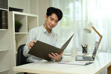 Yakışıklı bir erkek müşteri temsilcisi ofis masasındaki raporları kontrol ediyor..