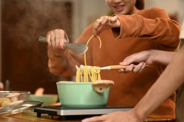 Genç çift mutfakta spagetti pişiriyor. İnsanlar, yemek ve ev hayatı kavramı.