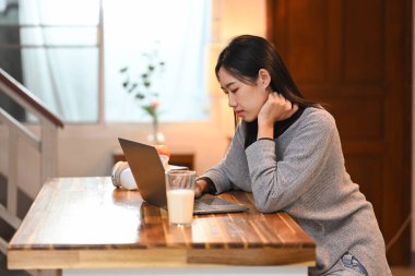 Mutfak masasında dizüstü bilgisayarla çalışan genç bir kadın..