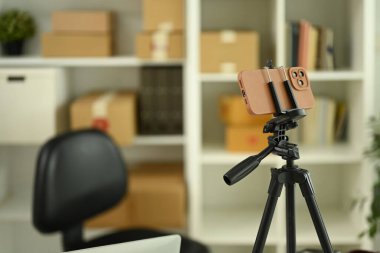 Evde ya da ofiste halkalı lamba, blog yazma ve video kaydetme ekipmanları olan bir tripoda yerleştirilmiş akıllı telefon.