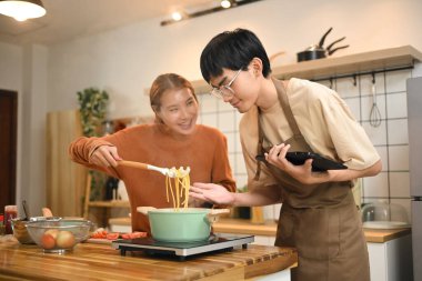 Hoş bir genç çift sıcak bir mutfakta öğle yemeği için spagetti hazırlıyor..