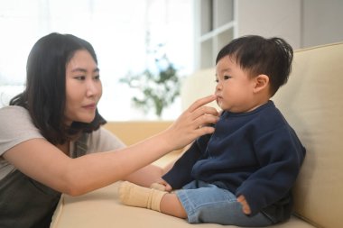 Gülümseyen anne bebek yüzüne nazikçe dokunuyor. Annelik ve çocuk bakımı kavramı.