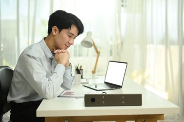 Çekici iş adamı ofis masasındaki finans raporunu analiz ediyor..