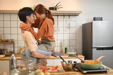 Sevecen genç çift mutfakta yemek pişirirken birlikte eğleniyor. Aşk, ilişkiler ve yaşam tarzı kavramı.