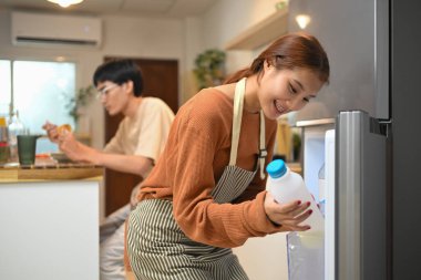Genç çift, sağlıklı kahvaltı hazırlamak için dolaptan bazı malzemeler alıyor..