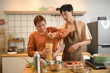 Mutlu genç çift ahşap tezgahta birlikte yemek hazırlıyor. İçi yemek malzemeleri dolu..