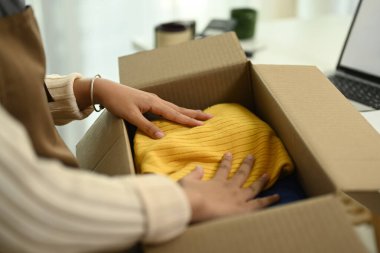 Küçük işletme sahibi müşteriye teslim etmek için ürünleri kutulara koyuyor. E-ticaret kavramı.