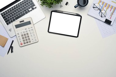 Üst görünüm dijital tablet, dizüstü bilgisayar, hesap makinesi ve belge beyaz masada.