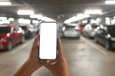 Yeraltı otoparkında beyaz ekranlı bir akıllı telefonu tutan..