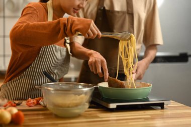 Genç çift mutfakta birlikte lezzetli bir yemek hazırlıyor. İnsanlar, yemek ve yaşam tarzı konsepti.