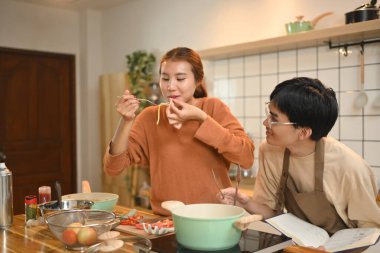 Genç çift, mutfakta birlikte yemek hazırlarken keyifli bir anın tadını çıkarıyor..