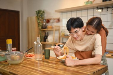Sevgi dolu genç bir çift mutfakta sıradan bir yemeğin tadını çıkarıyor. İnsanlar, yemek ve yaşam tarzı konsepti.