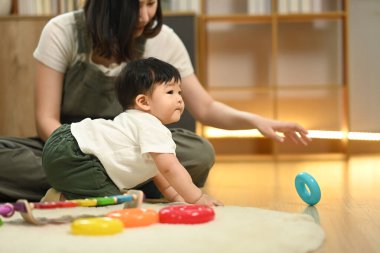 Sevgi dolu bir anne ve tatlı bir çocuk oturma odasında eğitici bir oyuncakla oynuyorlar..