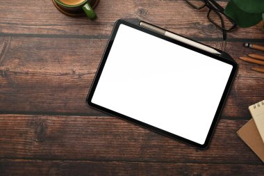 Üst görünüm dijital tablet boş ekran, bardaklar ve bir fincan kahve ahşap arka planda.